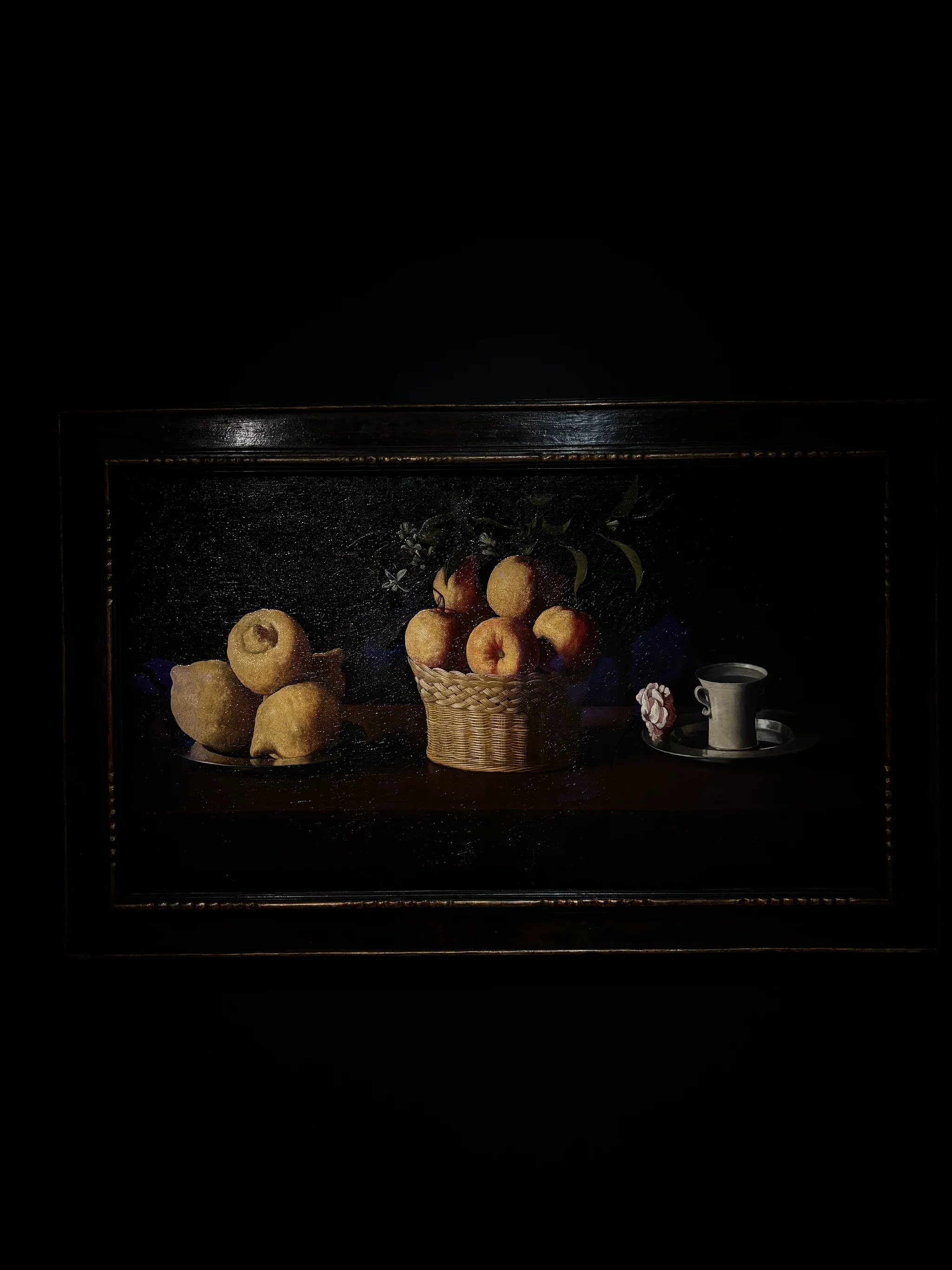 Francisco de Zurbarán, Still Life with Lemons, Oranges and a Rose. Four lemons on a pewter plate at left, a wicker basket of oranges with blossom at centre, and a cup of water on a silver dish with a single pink rose at right, arranged on a dark polished table against a black ground.
