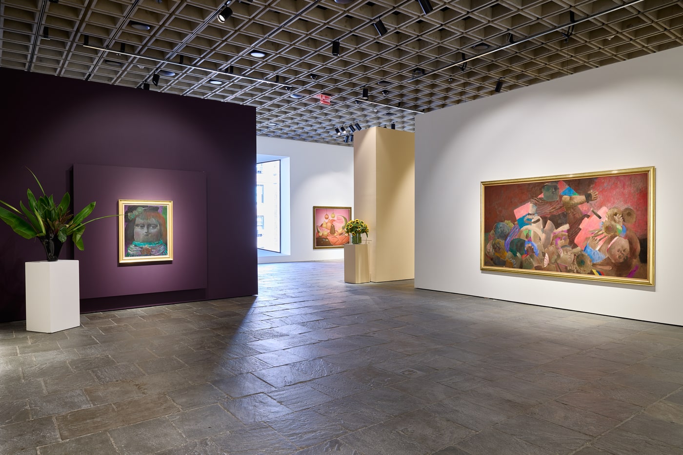 Aubergine wall at left carrying Mona Lisa, Age Thirteen in a gold frame, a pink-ground still life through the opening beyond, and at right a wide gold-framed crowd scene in reds and pinks. Sunflowers on a plinth. The Breuer building's coffered concrete ceiling and stone floor.